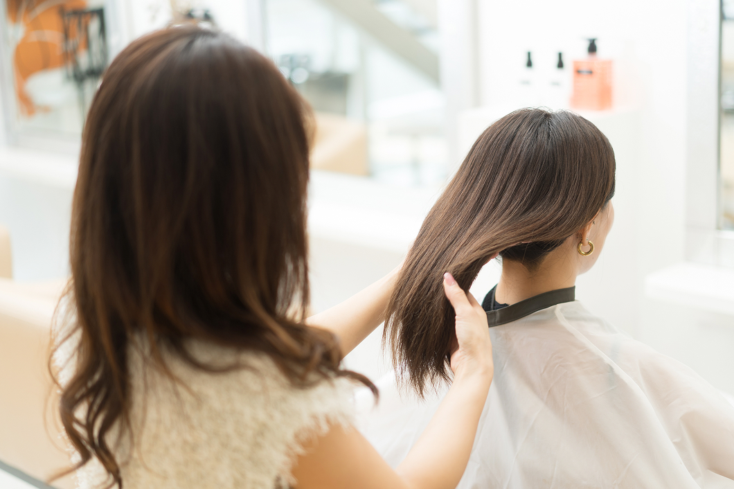 お客様の髪質を確認するスタイリスト