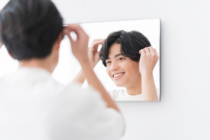 鏡でヘアスタイルを確認する男性